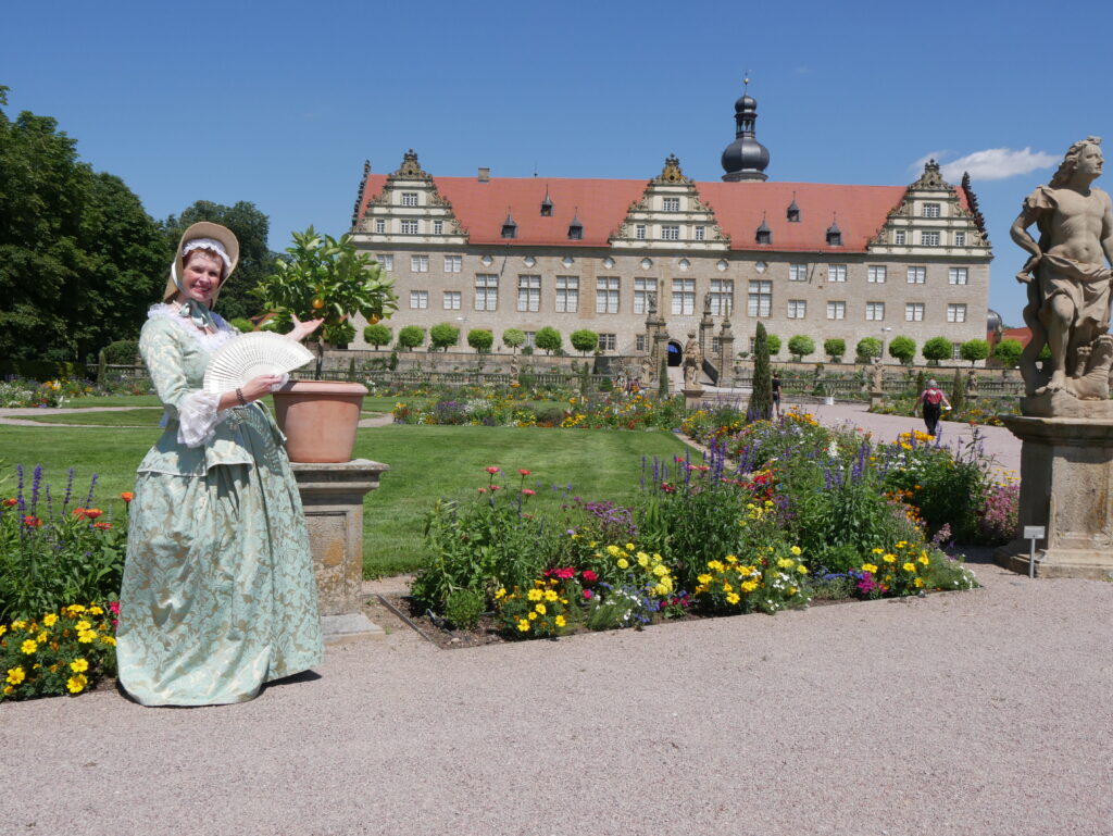 Ein Hoffräulein vor den blühenden Gärten des Schloss Weikersheim