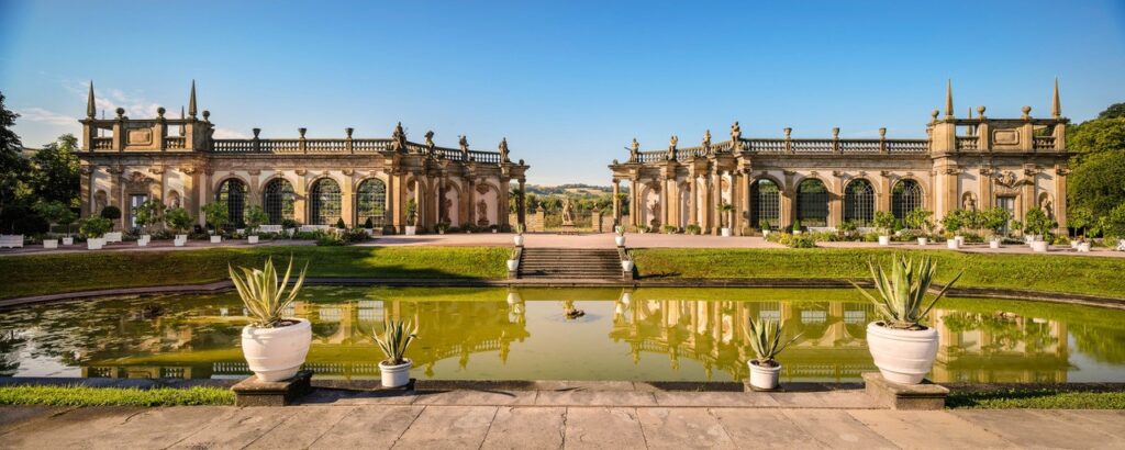 Die prachtvolle, zweitgeteilte Orangerie vor einem grünlichen See