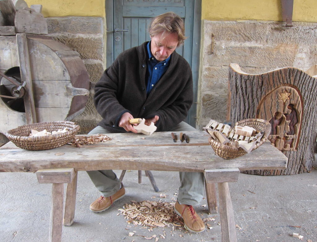 Ein Mann an einem Holztisch bei der Schnitzarbeit