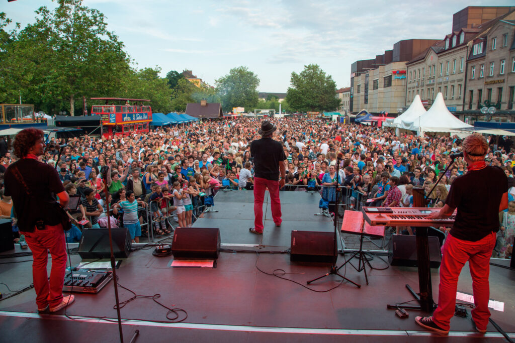 Blick von einer Bühne mit Band in ein großes Publikum unter freiem Himmel