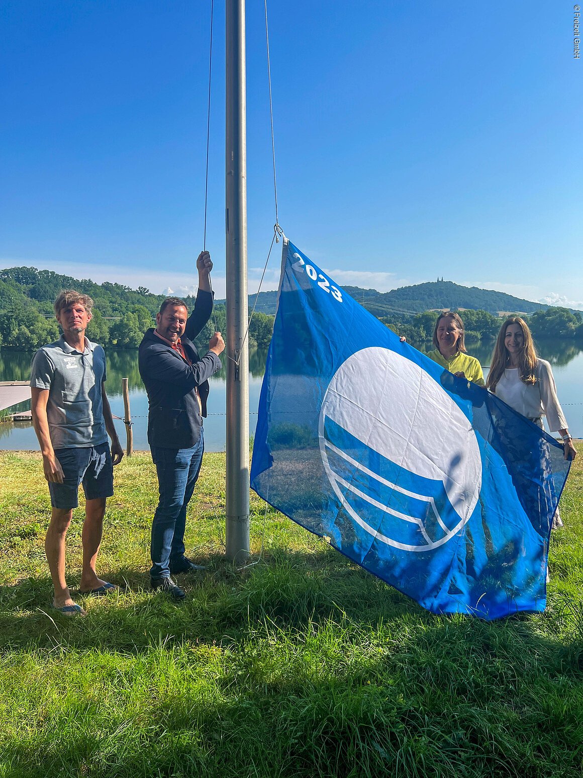Blaue Flagge Martin Lüders (Freizeit GmbH), Bürgermeister Mario Schönwald, Anne Schmitt (Flussparadies Franken) und Anne Schneider (Tourismusleiterin Bad Staffelstein) hissen gemeinsam die Blaue Flagge 2023 am Bad Staffelsteiner Ostsee.