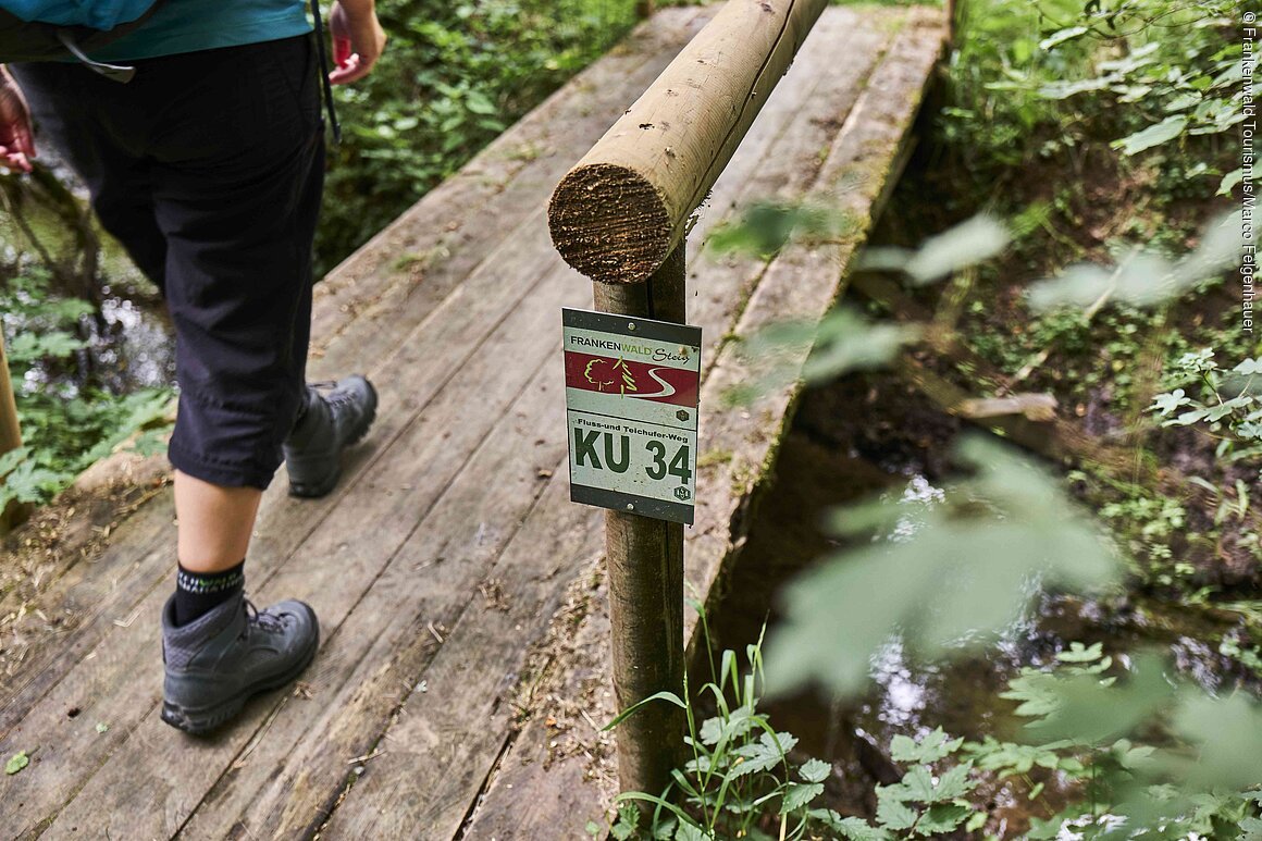 Das Bild zeigt die Beine eines Wanderers. Er läuft auf dem Frankenwald Steig.