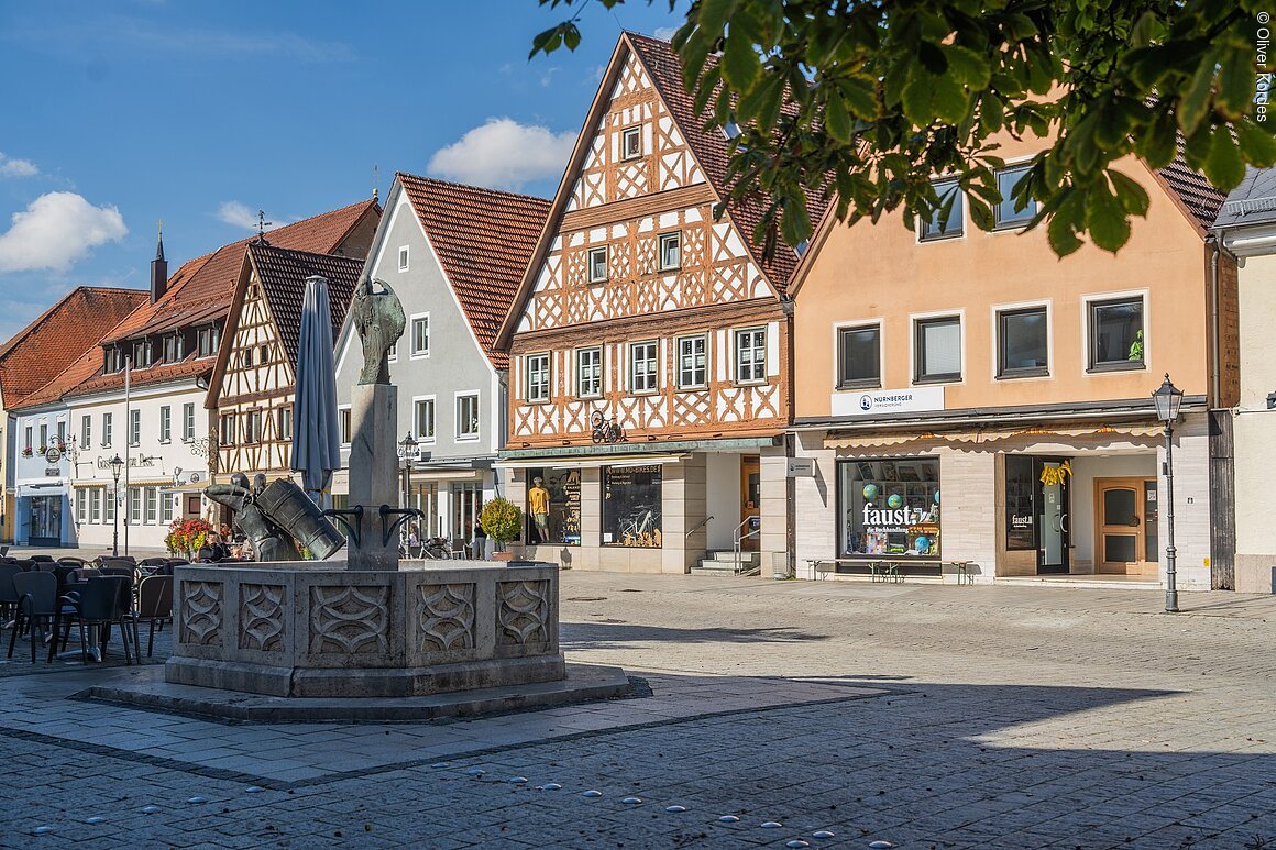 Marktplatz (Ebermannstadt, Fränkische Schweiz) Historischer Marktplatz mit Fachwerkhäusern und Brunnen, umgeben von Geschäften und Cafés.