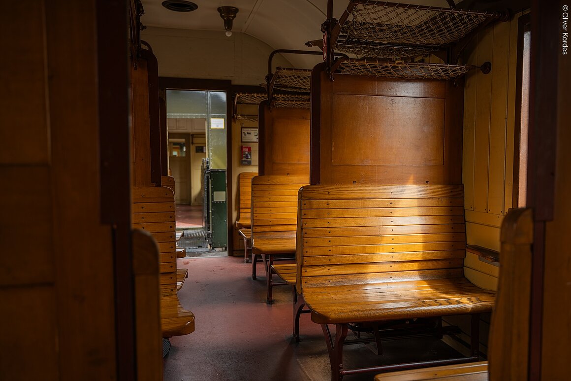 Dampfbahn (Ebermannstadt, Fränkische Schweiz) Innenraum eines historischen Zugwaggons mit Holzbänken und Gepäcknetzen.